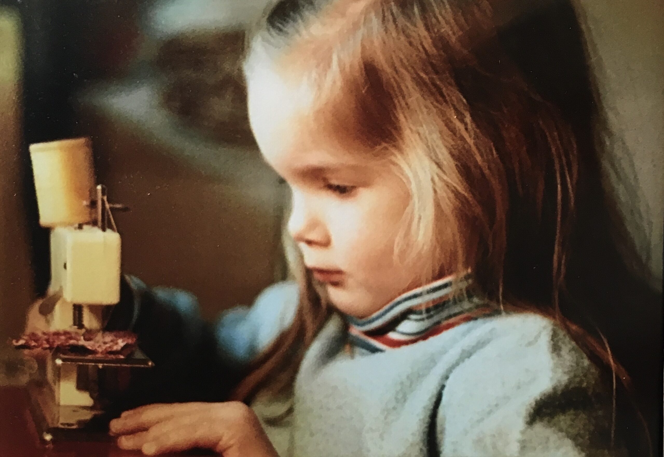 Close-up of a young child focused while learning to use a sewing machine